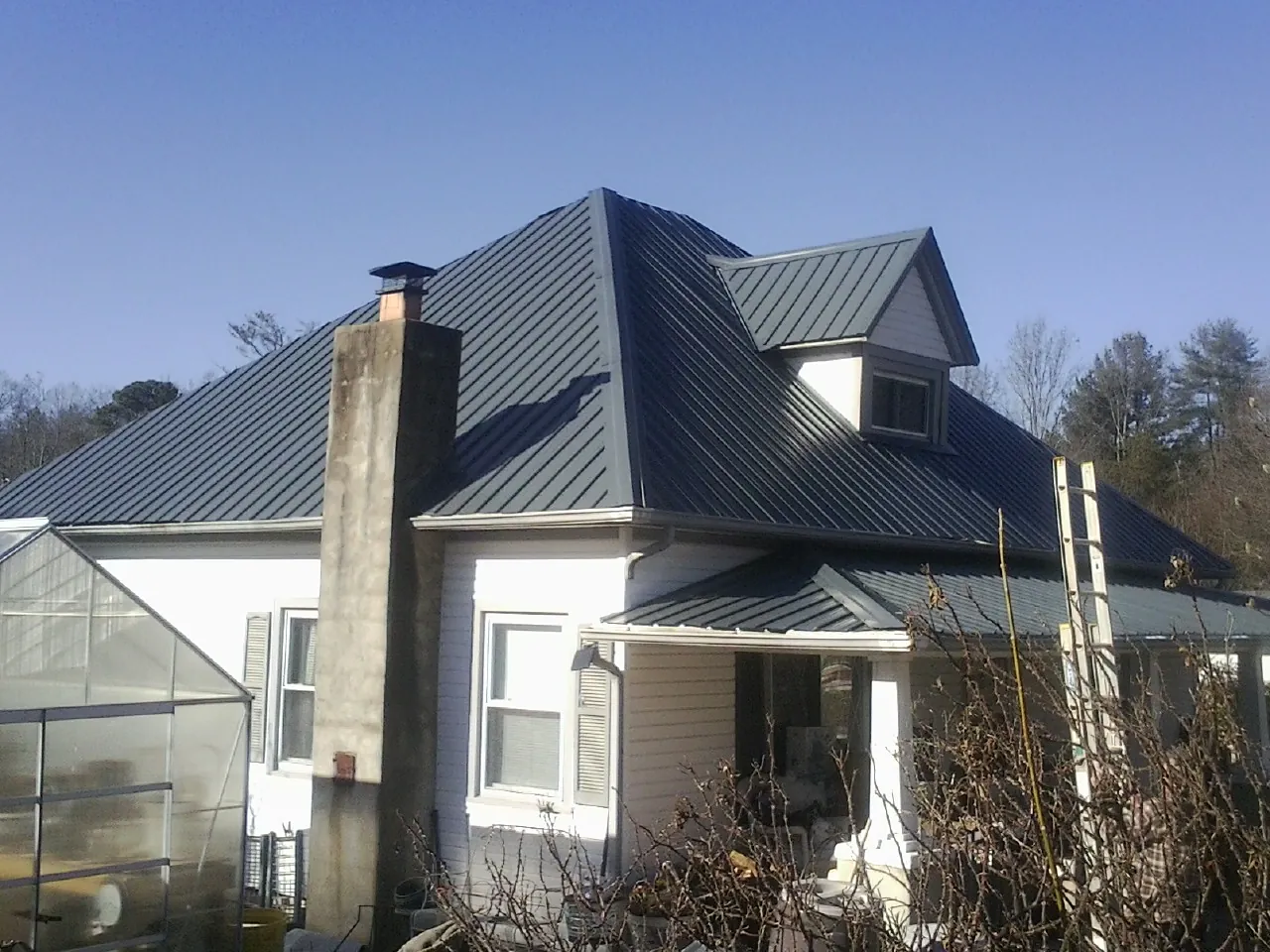 Dark blue standing seam metal roof on a white farmhouse with dormer — Slate & Tile Roof Repair by Roofing Brothers in Newark
