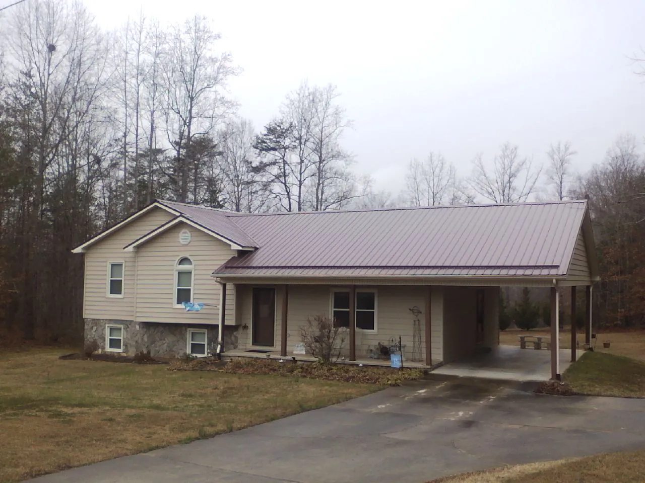 Burgundy metal roof on a tan split level home with an attached carport in Newark