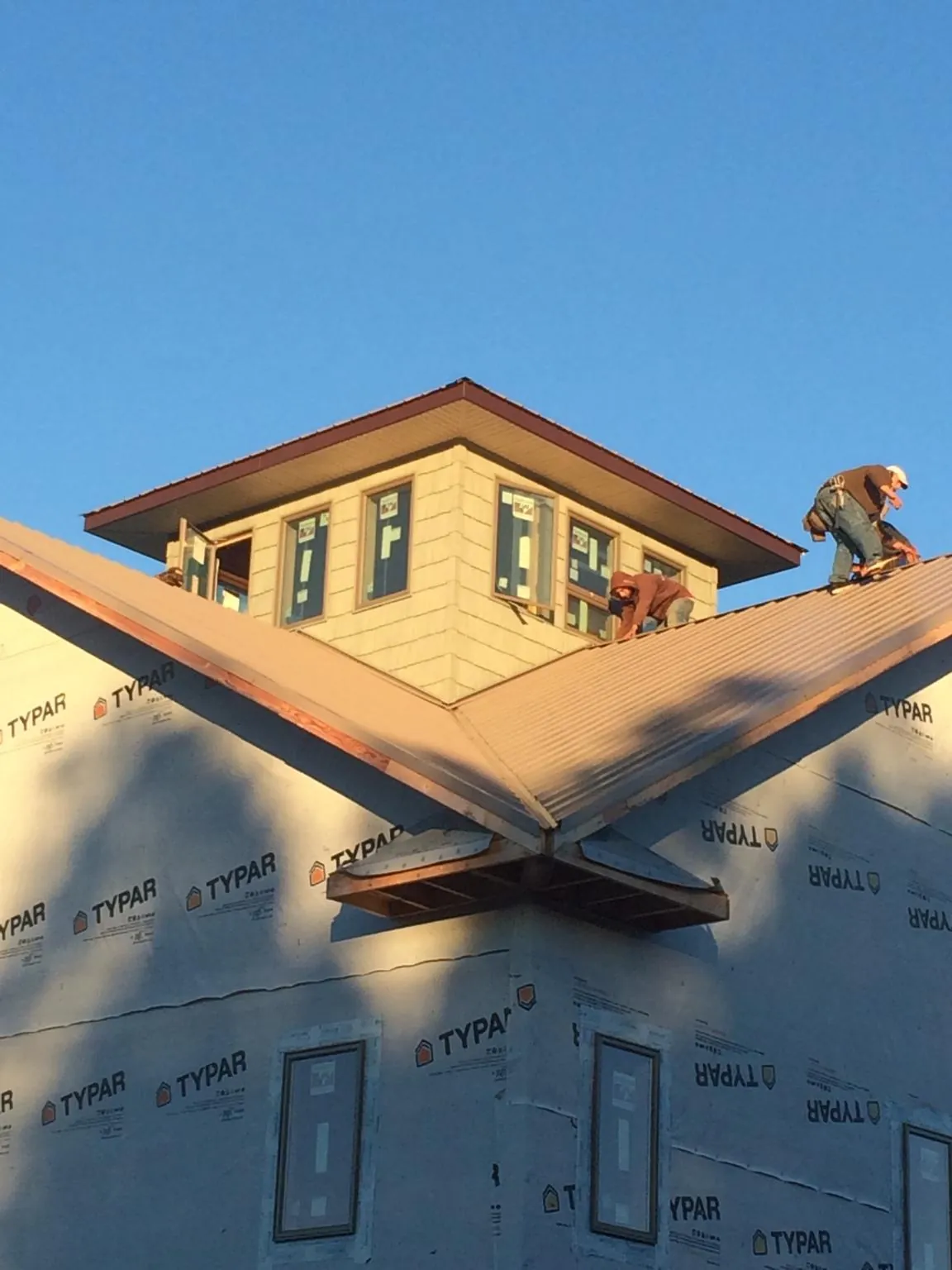 Roofers working around a rooftop cupola on a new metal roof at sunset — Roof Waterproofing in Newark by Roofing Brothers